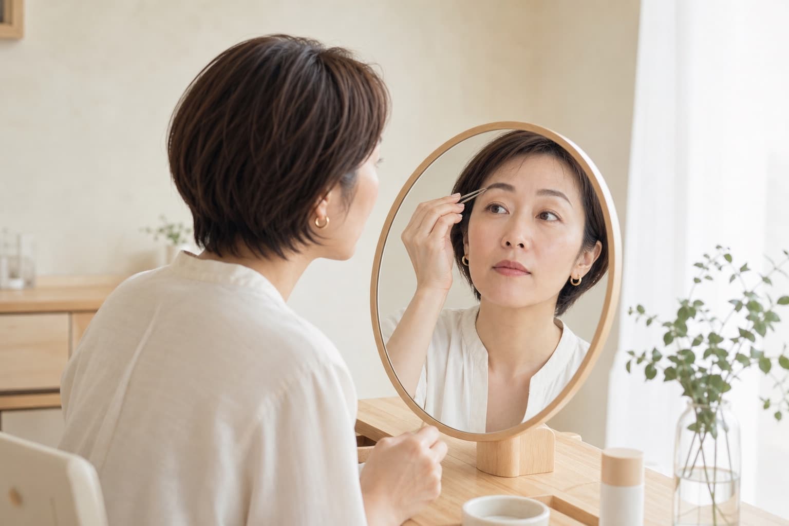 朝、鏡を見ながら眉を整える女性